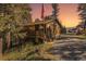 Charming home featuring a front porch, wood siding, and a gravel driveway surrounded by lush trees at 31084 Kings Valley Dr, Conifer, CO 80433