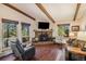 Cozy living room featuring a stone fireplace, hardwood floors, and large windows with scenic views at 31084 Kings Valley Dr, Conifer, CO 80433