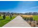 Concrete walking path surrounded by green grass, landscaping and modern homes in a well-kept community at 759 N Deer Park St, Watkins, CO 80137