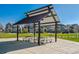 Outdoor picnic shelter and seating with multiple tables, next to homes and a green area at 759 N Deer Park St, Watkins, CO 80137