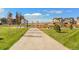 Sidewalk winding through a community park and green space, with trees, benches, playgrounds, and nearby single-Gathering homes at 759 N Deer Park St, Watkins, CO 80137