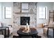 Living room with a rustic stone fireplace and large windows at 2442 Fox View Trl, Franktown, CO 80116