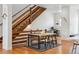 Stylish dining area adjacent to a wooden staircase, with a modern table and hardwood floors at 10165 E 59Th Ave, Denver, CO 80238