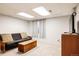Finished basement area with a couch, TV, and neutral carpet at 7883 S Windermere Cir, Littleton, CO 80120