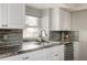 Bright kitchen featuring marble countertops, gray backsplash, and stainless faucet at 7883 S Windermere Cir, Littleton, CO 80120
