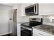 Modern kitchen features stainless steel appliances, white cabinets, and stone countertops at 7883 S Windermere Cir, Littleton, CO 80120