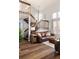 Bright and airy living room with a leather sofa, hardwood floors, and a wooden staircase at 7883 S Windermere Cir, Littleton, CO 80120