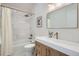 A well-lit bathroom with white tile, a shower-tub combo, and a stylish wood vanity at 3649 W 21St Ave, Denver, CO 80211