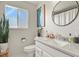 Bright bathroom featuring a modern vanity, round mirror, and ample natural light from the frosted glass window at 265 N Holcomb St, Castle Rock, CO 80104