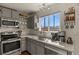 Well-lit kitchen featuring stainless steel appliances, grey cabinets, and a window overlooking the neighborhood at 265 N Holcomb St, Castle Rock, CO 80104