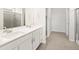 A modern bathroom with double sinks, white cabinets and countertops, and a tiled floor at 9069 Pitkin St, Commerce City, CO 80022