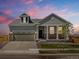 Charming single-Gathering home with a two-car garage, inviting front porch and manicured lawn at dusk at 9069 Pitkin St, Commerce City, CO 80022