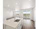 Open-concept kitchen with island, stainless steel appliances, and views of the outdoor deck at 9069 Pitkin St, Commerce City, CO 80022