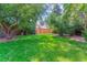 Spacious back yard featuring a large lawn, mature trees, and a wooden fence at 6330 E Vassar Ave, Denver, CO 80222