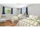 Bright bedroom features two twin beds with green-striped bedding, hardwood floors, and plenty of natural light at 6330 E Vassar Ave, Denver, CO 80222