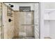 Shower with glass door and tan stone tile, with seating and a dark showerhead at 6330 E Vassar Ave, Denver, CO 80222