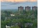 A mountain view above a treeline, with luxury apartment buildings nestled behind lush green trees at 3131 E Alameda Ave # 1107, Denver, CO 80209