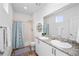 Bright bathroom featuring double vanity, granite counters, and shower with blue patterned curtain at 1106 Oak Cir, Lakewood, CO 80215