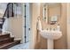 Elegant powder room featuring a pedestal sink, round mirror, and staircase access at 3181 Firenze Pl, Highlands Ranch, CO 80126