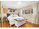 Bright bedroom with hardwood floors, large windows, and a white storage bench at the foot of the bed at 882 E Briarwood Cir, Centennial, CO 80122
