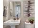 A bathroom with white pedestal sink, modern rectangular mirror and artwork at 14667 Crouch Pl, Parker, CO 80134