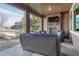 Back covered patio area with a stone fireplace, mounted television, and comfortable outdoor seating at 14667 Crouch Pl, Parker, CO 80134