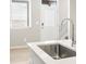 Close-up of a kitchen sink and faucet with the front door and blinds visible in the background at 6512 N Malaya St, Aurora, CO 80019