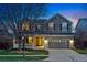 Charming two-story home at dusk featuring a welcoming front porch and a two-car garage with beautiful lawn at 7430 E Bayaud Ave, Denver, CO 80230