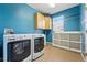 Laundry room with blue walls, washer, dryer, and storage shelves at 7430 E Bayaud Ave, Denver, CO 80230
