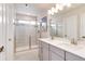This bathroom offers a dual sink vanity, glass-enclosed shower with decorative tile and modern fixtures at 9804 Rosalee Peak St, Littleton, CO 80125