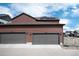 Home's exterior view showcasing a three car garage with dark gray doors and solar panels at 9804 Rosalee Peak St, Littleton, CO 80125