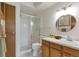 Well-lit bathroom with a glass-enclosed shower, single sink vanity, and round mirror at 13606 E Bates Ave # 304, Aurora, CO 80014