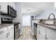 Open kitchen with stainless steel appliances, white cabinets, and modern tile backsplash at 2281 Vaughn # 104A, Aurora, CO 80014