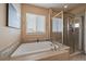 Relaxing bathroom featuring a soaking tub, a separate glass enclosed shower, and neutral tiling at 7635 Weaver Cir, Castle Rock, CO 80104