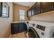 Well-equipped laundry room with modern washer and dryer, dark cabinets, and a utility sink at 7635 Weaver Cir, Castle Rock, CO 80104