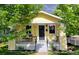 Charming yellow home featuring a cozy front porch with decorative hanging plants and a black front door at 3196 S Logan St, Englewood, CO 80113