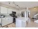 Modern kitchen features white cabinets, stainless steel appliances, a center island, and easy access to the staircase at 19372 E 41St Ave, Denver, CO 80249
