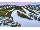 Extensive ski area and log home with solar panels, set against snowy mountains and lush forests from an aerial perspective at 422 Timber Trail Rd, Breckenridge, CO 80424