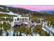 Aerial view reveals a mountain ski resort and stunning log home, surrounded by lush pine forests and snowy ski slopes at 422 Timber Trail Rd, Breckenridge, CO 80424