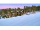 Exterior view of a log home nestled among pine trees, adjacent to a snowy ski slope, with a backdrop of mountains at 422 Timber Trail Rd, Breckenridge, CO 80424