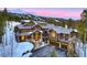 Stunning log home featuring a stone base, grand entrance, and a heated driveway with a backdrop of snow-capped mountains at 422 Timber Trail Rd, Breckenridge, CO 80424