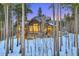 Secluded log home framed by tall pine trees, showcasing a stone chimney, and snowy landscape with mountain views at 422 Timber Trail Rd, Breckenridge, CO 80424