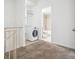 Carpeted laundry room area featuring a washing machine and view into bathroom at 384 S Ironton St # 413, Aurora, CO 80012