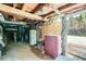 Unfinished basement with exposed wood beams, water heater, and doorway to the outside at 27389 Highway 74, Evergreen, CO 80439