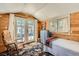 Bedroom featuring wood walls, a single bed, an outdoor view through French doors, and cozy decor at 27389 Highway 74, Evergreen, CO 80439