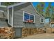 The home's exterior is a charming stone foundation, gray wood siding, and flower boxes under the windows at 27389 Highway 74, Evergreen, CO 80439