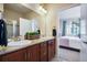 Well-lit bathroom featuring double sinks, granite countertops, wood cabinets, and access to the primary bedroom at 16022 W 63Rd Ln # A, Arvada, CO 80403