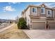 Exterior view of a multi-story townhome with a two-car garage and landscaping at 16022 W 63Rd Ln # A, Arvada, CO 80403