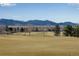 Expansive golf course view with distant mountains, trees, and residential homes under a clear blue sky at 16022 W 63Rd Ln # A, Arvada, CO 80403