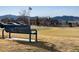 Scenic golf course view featuring a clubhouse, mountain backdrop, and a blue bench in the foreground at 16022 W 63Rd Ln # A, Arvada, CO 80403